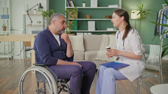 A Middleaged Man in a Wheelchair Talking to a Nurse