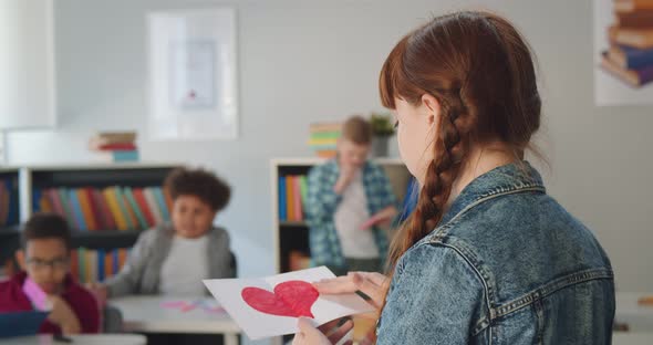 Close Up of Preteen Schoolgirl Holding Paper with Red Painted Heart Standing in Classroom