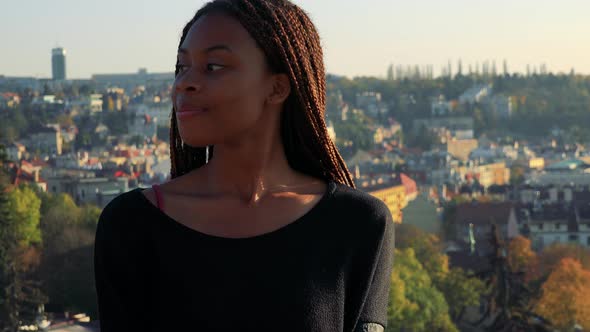 Young Beautiful Black Woman Smiles To Camera - City in the Background