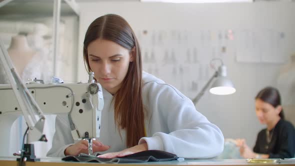 Front View Of Female Fashion Designer Working With Sewing Machine In Workshop