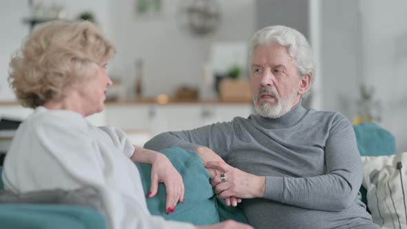 Old Man Talking To Beautiful Old Woman Sitting on Sofa at Home