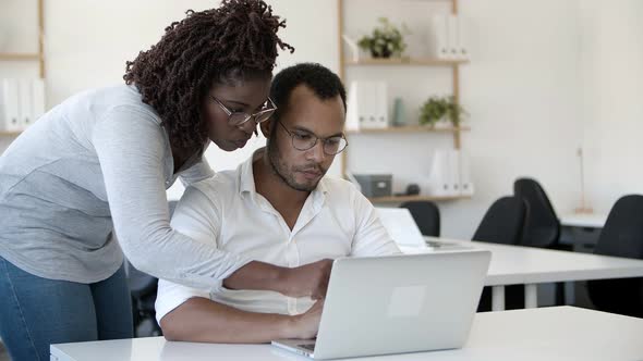 Thoughtful Colleagues Talking and Looking at Screen of Laptop