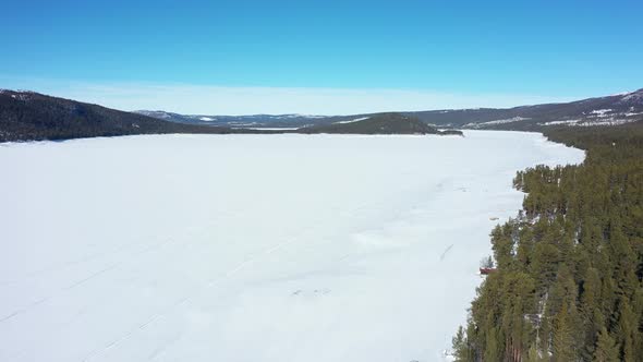 Flying over massive snow covered freshwater lake Tunhovdfjord looking over island at Palsbufjord in