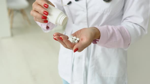 Female Doctor in White Coat Takes Pills Out of a Jar