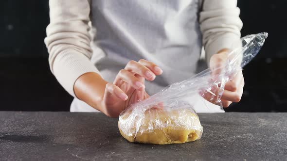 Woman wrapping dough in a plastic wrap