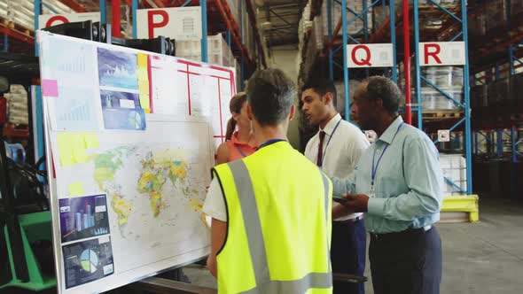 Warehouse staff in discussion at an information board 4k