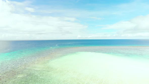 horizon drone shot of turquoise swallow water in  tropical Pacific ocean under blue sky and white cl