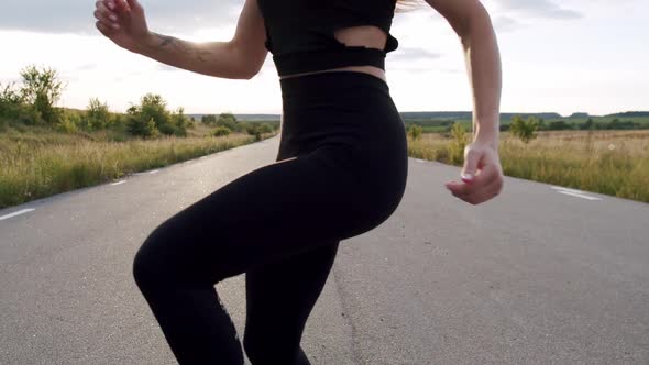 Roundabout View of Athletic Girl Training Jumps on a Road at Summer Nature