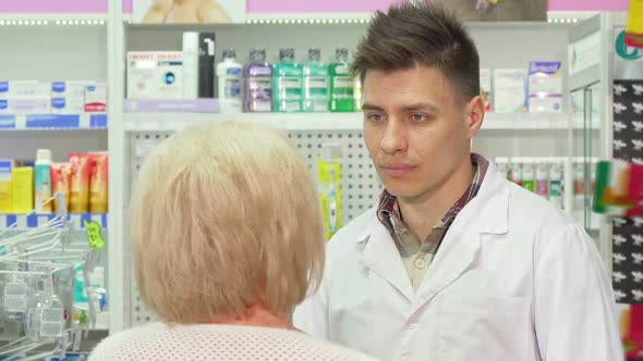 Young Male Pharmacist Talking To His Elderly Client