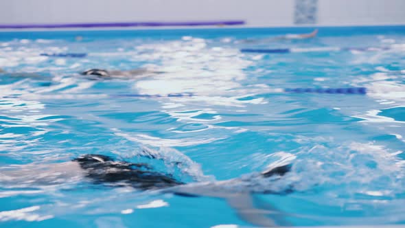 Swimming Lessons for Children in the Pool - Beautiful Fair-skinned Girl Swims in the Water