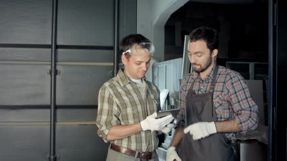 Two Carpenters Have a Discussion Using Digital Tablet