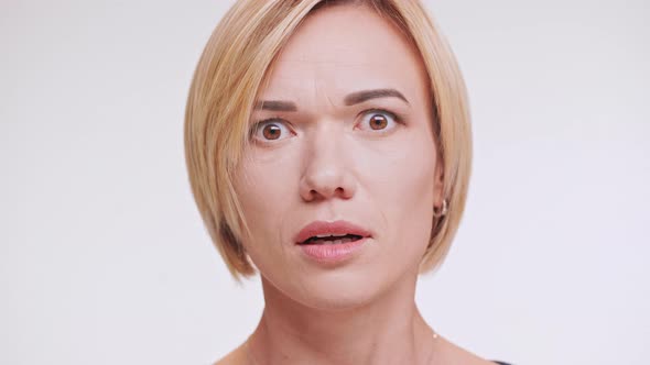 Close Up Footage of Afraid Caucasian Female with Blonde Hair Standing on White Background in Shock