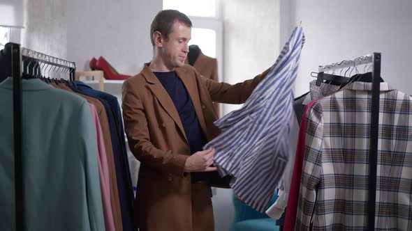 Portrait of LGBT Man Narcissist Examining Shirt in Shop Indoors Dropping Hanger in Slow Motion