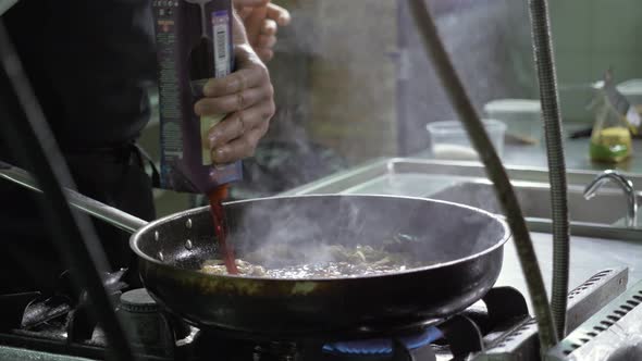 Chef is Making Flambe Sauce on Restaurant Kitchen with Onion and Wine