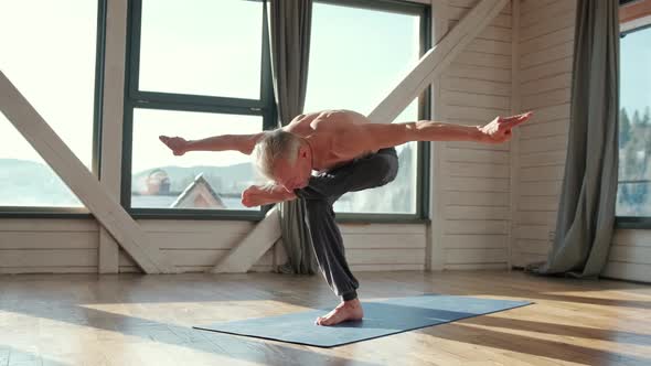 Mature Man Amongst Doing Power Yoga Exercises.