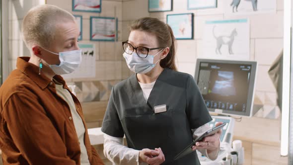 Vet Using Tablet and Talking with Client in Clinic