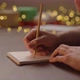 Orbit Shot of Man Writes New Year Goals in Notepad with a Pencil Under Warm Light in the Evening - VideoHive Item for Sale