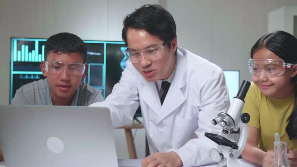 Young Asian Boy And Girl Learning Science Experiment In Laboratory With Teacher In Classroom