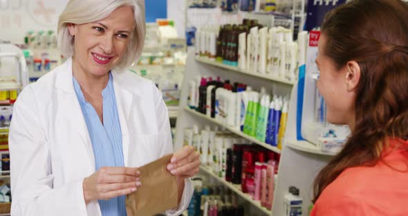 Pharmacist packing medicine in paper bag for customer