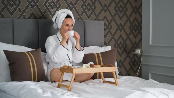 Beautiful Woman Having Breakfast in a Hotel Bed