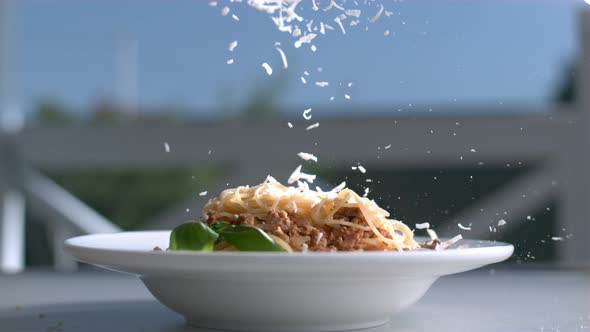 Pasta With Cheese Plate On A Table And Parmesan Is Falling On Spaghetti In Slow Motion