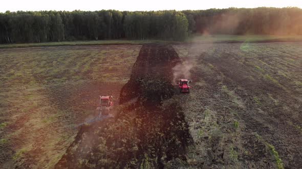 Two tractors plow a field