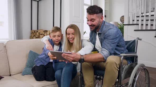 Friendly Mother, Son and Dad in Wheelchair which Celebrating Victory in Video Game