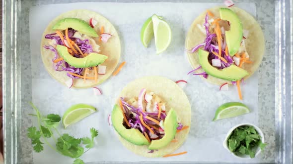 Fresh fish tacos with cod and purple cabbage on a white corn tortillas.