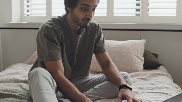 Man Using Laptop on Bed