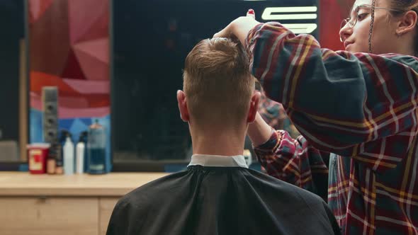 Barbershop: a woman barber cuts a client's man's hair