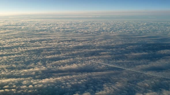 Incredible view from the cockpit of an airplane flying high above the clouds leaving a long white co