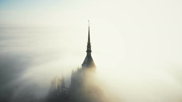 Drone Flying Above Majestic Golden Statue on Top of Mont Saint Michel Castle Spire Above Sunshine