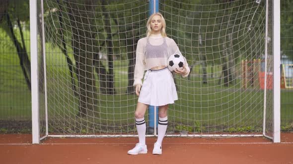 Elegant Beautiful Woman Posing with Ball at Football Goal. Portrait of Confident Blond Caucasian