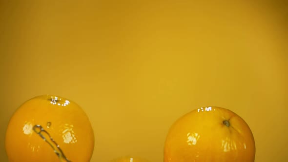 Group of Oranges are Bouncing From Water with the Splashes on Yellow Background