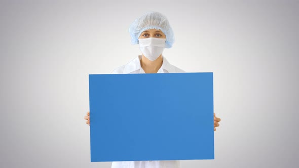 Woman Doctor in a Mask Holding an Empty Board on Gradient Background