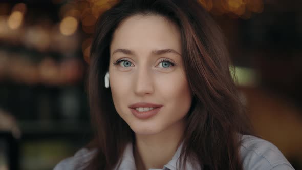 Woman in Earphones Smiling and Looking at Camera at Cafe