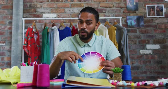 Mixed race male fashion designer showing colours pallet looking at camera and smiling