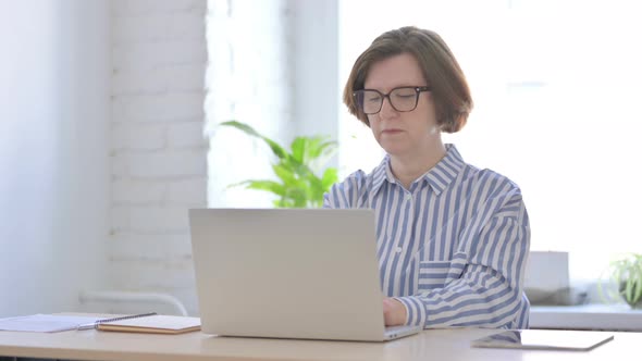 Senior Woman Looking at Camera While Using Laptop