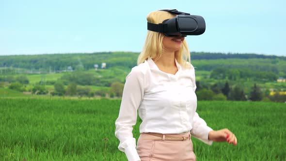 Young Attractive Blond Woman Puts on Virtual Reality Glasses - Countryside