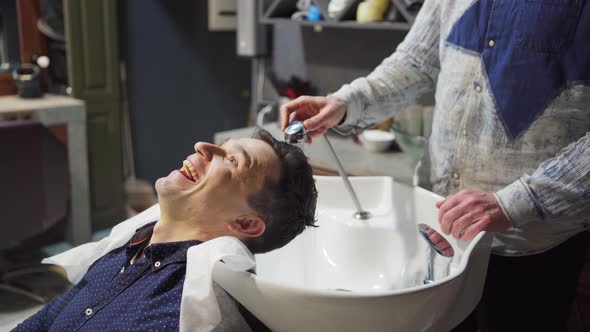 a Brunet Man Washes Hair with a Hairdresser in a Barbershop