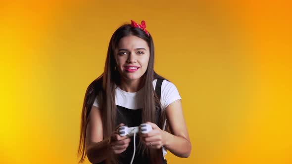 Pretty Young Girl Playing Video Exciting Game on Tv with Joystick on Yellow 