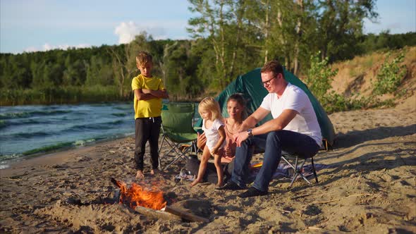 Parents and Kids Warming By the Fire in Camp