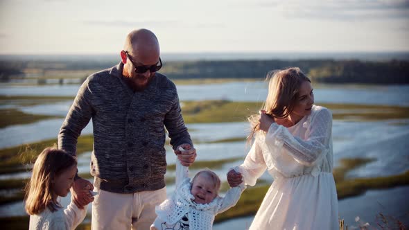 Young Family Standing on the Wheat Field - Father and Mother Holding Hands with Their Baby and