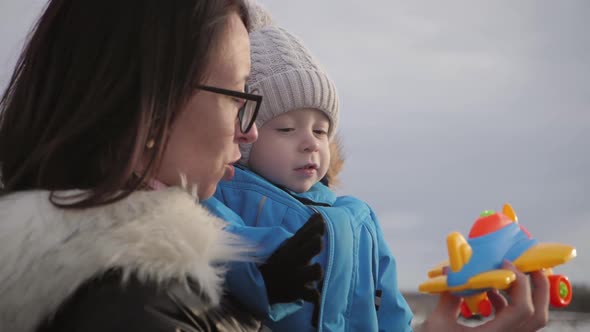 Happy Mother with Little Son Playing with Toy Plane at Sunset Mother and Child Hugging