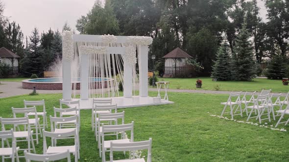 beautiful wedding arch in the park with white chairs