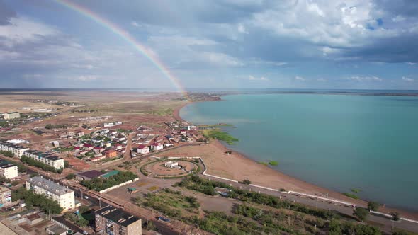 Bright Rainbow and Rain Over the City Near Lake