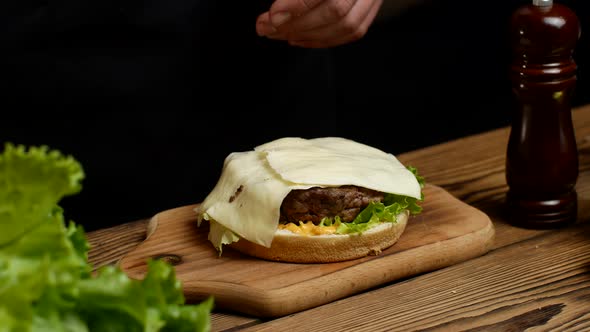 Closeup of the Hands of the Chef Put Various Ingredients Alternately on the Bun for an Appetizing