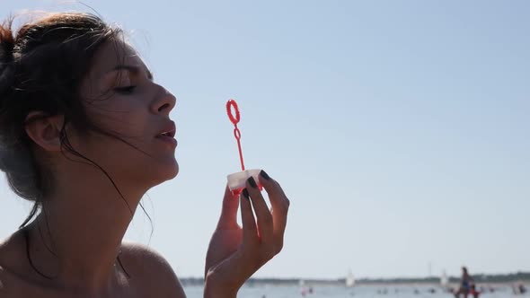 Caucasian young brunette blowing soap bubbles on ocean beach  slow-mo  1920X1080 HD video - Happy fe