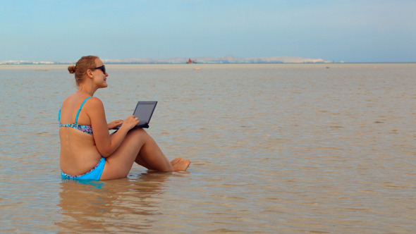 Woman Using Laptop Sitting in  Sea