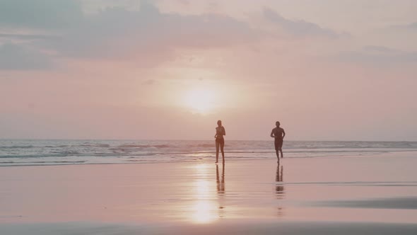 People Jogging on Beach at Sunset